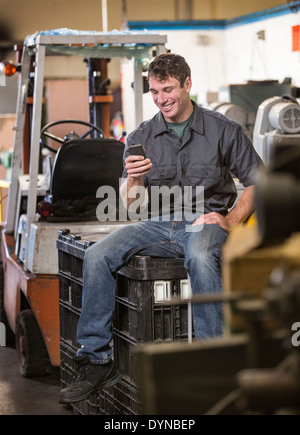 Caucasian worker using cell phone in warehouse Banque D'Images