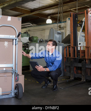 Caucasian businessman examinant boxes in warehouse Banque D'Images