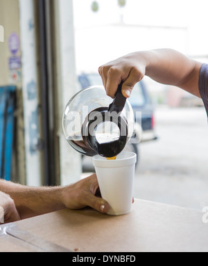 Ouvriers qui déversent de la tasse de café à l'entrepôt Banque D'Images