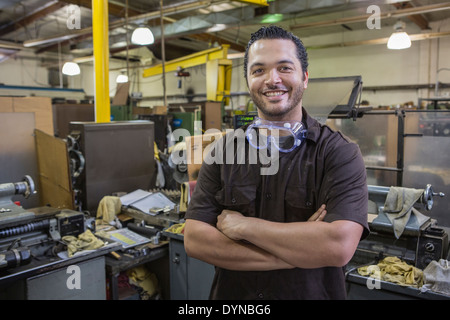 Hispanic worker smiling in repair shop Banque D'Images