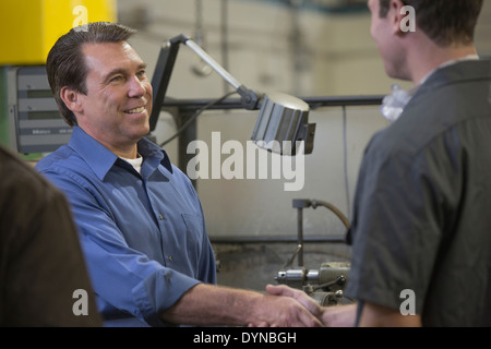 Travailleur et manager shaking hands in warehouse Banque D'Images