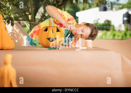 Caucasian boy decorating jack o'lantern Banque D'Images