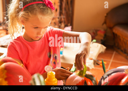 Caucasian girl decorating jack o'lantern Banque D'Images