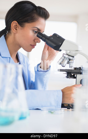 Hispanic scientist using microscope in laboratory Banque D'Images