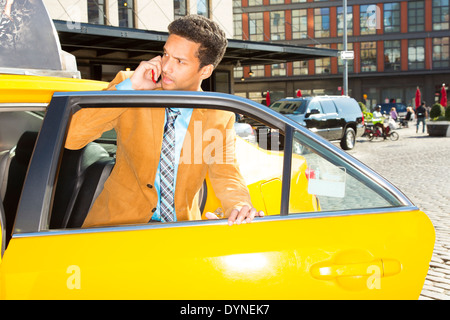 Mixed Race woman climbing out of taxi Banque D'Images