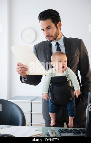 Businessman working with baby in office Banque D'Images