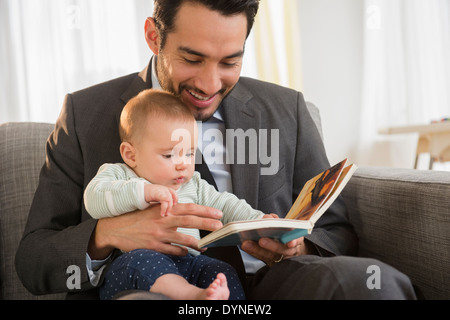 Père lecture pour bébé sur canapé Banque D'Images