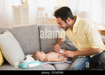 Père de changer la couche de bébé sur canapé Banque D'Images