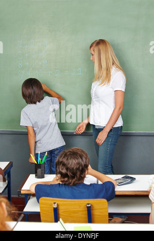 Garçon résoudre problème de mathématiques à l'école primaire à classe chalkboard Banque D'Images