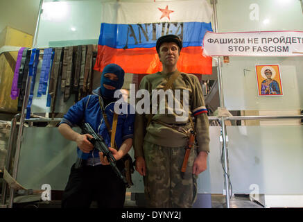 Lugansk, Ukraine. Apr 23, 2014. Pro-Russian garde des hommes armés d'une entrée de l'office régional de la sécurité publique avec un drapeau national russe est en arrière-plan --- les militants pro-russe troué vers le haut dans le bureau régional de l'Ukraine d'un service de sécurité à Luhansk et refusé de déposer les armes et a juré de se battre. Crédit : Igor Golovnov/Alamy Live News Banque D'Images