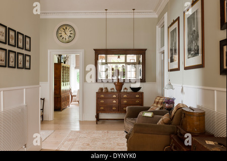 Tiroirs en bois ancien et de miroir dans le couloir avec des fauteuils en cuir et des lignes vintage Banque D'Images