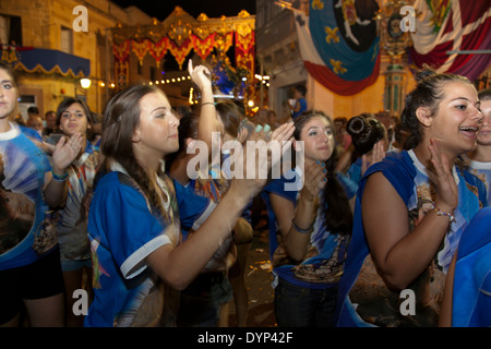 Les jeunes femmes clap et de la danse à la musique de fanfare au cours d'une ville traditionnelle fête à Malte. Banque D'Images