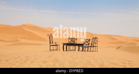 Une table et des chaises fixées sur parmi les dunes de sable de l'Erg Chebbi, Maroc, au bord du désert du Sahara. Banque D'Images