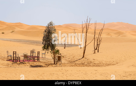 Une table et des chaises fixées sur parmi les dunes de sable de l'Erg Chebbi, Maroc, au bord du désert du Sahara. Banque D'Images