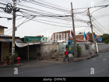 Une petite rue vide à Bangkok, en Thaïlande, avec un signe du temple sur la gauche. Vieux poteaux de téléphone et câbles électriques sont considérés ici Banque D'Images