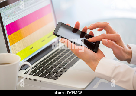 Businesswoman typing message on mobile phone in office. Banque D'Images