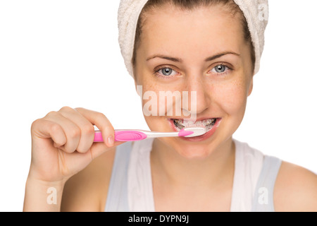 Teenage girl with braces se brosser les dents sur fond blanc Banque D'Images