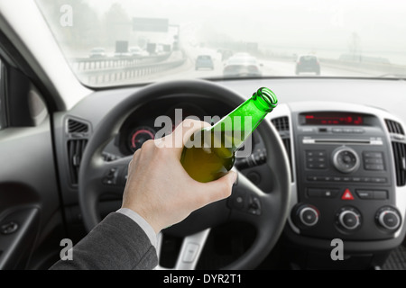 Man hand holding bouteille de bière en driving car Banque D'Images