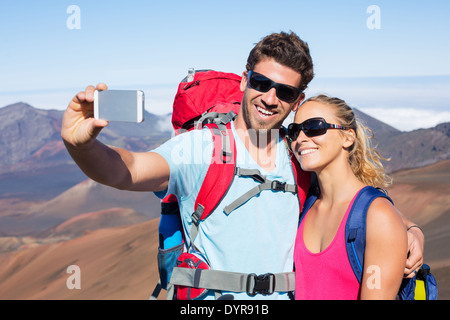 Heureux couple taking photo d'eux-mêmes avec smart phone outdoors, prendre un "70623" Banque D'Images