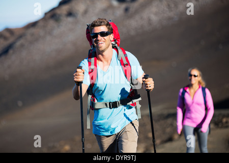 Randonnée dans les montagnes. Heureux couple athlétique avec sacs à dos randonnée bénéficiant à l'extérieur sur sentier de montagne magnifique. Banque D'Images