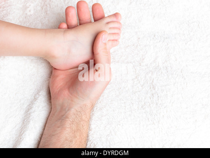 Père tenir doucement la jambe du bébé dans la main Banque D'Images