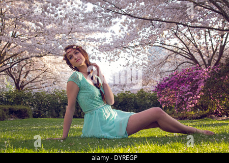 Belle jeune femme admirant les fleurs de printemps dans le parc Banque D'Images