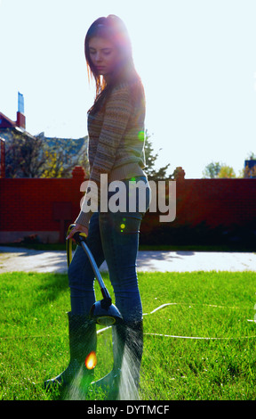 Portrait en pied de la femme est d'arroser un jardin Banque D'Images