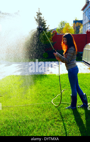 Portrait en pied de la femme est d'arroser un jardin Banque D'Images