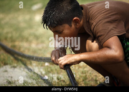 Dhaka, Bangladesh. Apr 25, 2014. Un garçon l'eau potable de la conduite d'eau tout en jouant sur le terrain.Les gens dans la capitale a connu la journée la plus chaude dans les 54 dernières années comme le mercure a grimpé à 40,7 degrés Celsius hier, le Met Office dit.La précédente la température la plus élevée a été enregistrée dans la capitale 42,3 degrés le 30 avril 1960, selon le Bangladesh Meteorological Department. La température la plus élevée le 24 avril l'année dernière à Dhaka a été 34,2 degrés. Zakir Hossain Chowdhury Crédit :/NurPhoto ZUMAPRESS.com/Alamy/Live News Banque D'Images