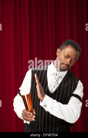 Bien habillé, l'homme pourrait être un barman, faisant des références avec sa bière Banque D'Images