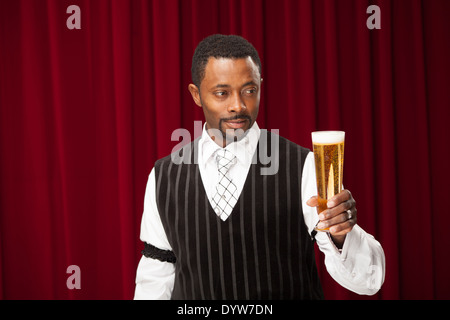 Bien habillé, l'homme pourrait être un barman, faisant des références avec sa bière Banque D'Images