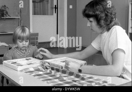 Berlin, DDR, les éducateurs jouant avec une petite fille un jeu de placement Banque D'Images