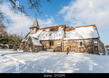 L'église de St Nicholas, Pyrford, Surrey, UK dans la neige en hiver au soleil avec ciel bleu Banque D'Images