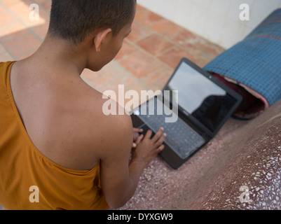 Jeune moine bouddhiste à l'aide d'un ordinateur portable au barrage de Wat Temple Nak, Siem Reap, Cambodge Banque D'Images