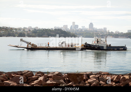 Un remorqueur poussant une barge avec un van sur elle dans le port de Sydney, Australie Banque D'Images