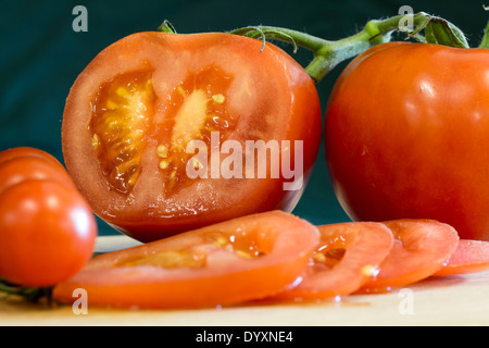 Portrait de quatre tranches de tomate rouge sur une planche à découper en bois. Quatre tomates et la moitié de la chair et les graines de tomate montrant Banque D'Images