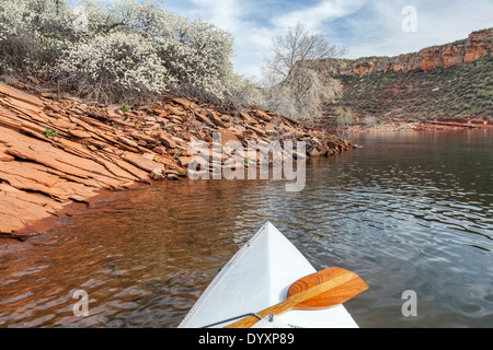 Spingtime canoe - canoe kayak avec une pagaie sur Horsetooth Reservoir près de Fort Collins, Colorado dans un paysage de printemps Banque D'Images