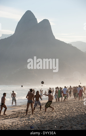 Rio de Janeiro, Brésil. Deux frères (montagne) Dois Irmãos et beaucoup de clubs de football brésilien mad men jouant au football sur la plage dans l'après-midi. Banque D'Images