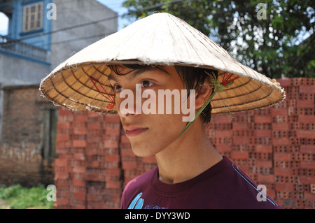 Teenage boy'portant un chapeau conique au Vietnam pour abriter du soleil Banque D'Images