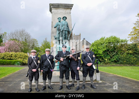 Cinq hommes portant des fusils, une mitrailleuse et se tenir en face d'un WW1 war memorial Banque D'Images