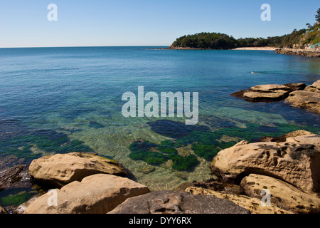 Vue depuis à travers le calme bleu océan translucide de l'eau à une pointe de la baie de sable isolée sur une parfaite journée ensoleillée Australie Banque D'Images