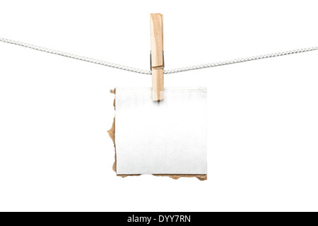Morceau de carton déchiré accroché sur un conseil clothespin, isolé sur blanc. Banque D'Images