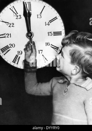 Enfant avec une horloge sur le réveillon du Nouvel An 1933 Banque D'Images