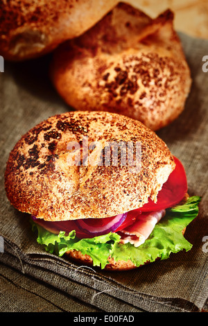 Burger fait maison rustique sur le tissu. Brioches sur l'arrière-plan. Selective focus, compositions verticales, des couleurs vives. Banque D'Images