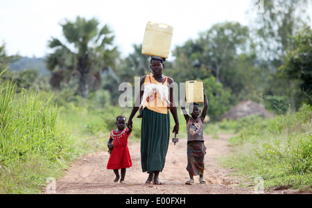 Les jeunes enfants du village de terminer leur journée de congé par la collecte de l'eau sale pour leurs familles dans le district de Lira d'Ouganda du Nord Banque D'Images