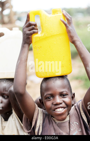 Les enfants de recueillir l'eau d'une source d'eau du gouvernement d'impur dans le Kosovo bidonville de la ville de Kampala en Ouganda. Banque D'Images