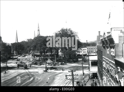 Cette photographie historique capture Central Square à Keene, dans le New Hampshire, avec ses rues animées, son cheval et son buggy, et l'emblématique Keene Electric Railroad. L'image offre un aperçu de la vie en Nouvelle-Angleterre au début du XXe siècle. Banque D'Images