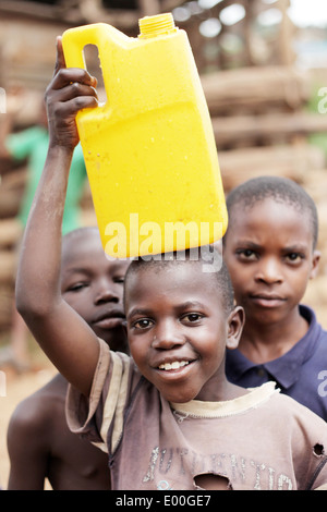 Les enfants de recueillir l'eau d'une source d'eau du gouvernement d'impur dans le Kosovo bidonville de la ville de Kampala en Ouganda. Banque D'Images