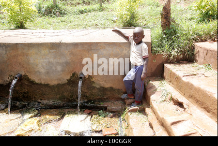 Les enfants de recueillir l'eau d'une source d'eau du gouvernement d'impur dans le Kosovo bidonville de la ville de Kampala en Ouganda. Banque D'Images