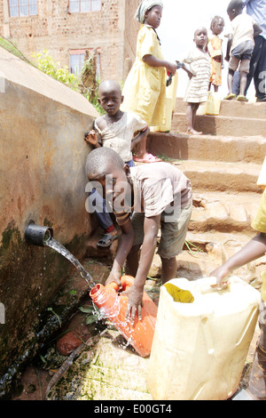 Les enfants de recueillir l'eau d'une source d'eau du gouvernement d'impur dans le Kosovo bidonville de la ville de Kampala en Ouganda. Banque D'Images